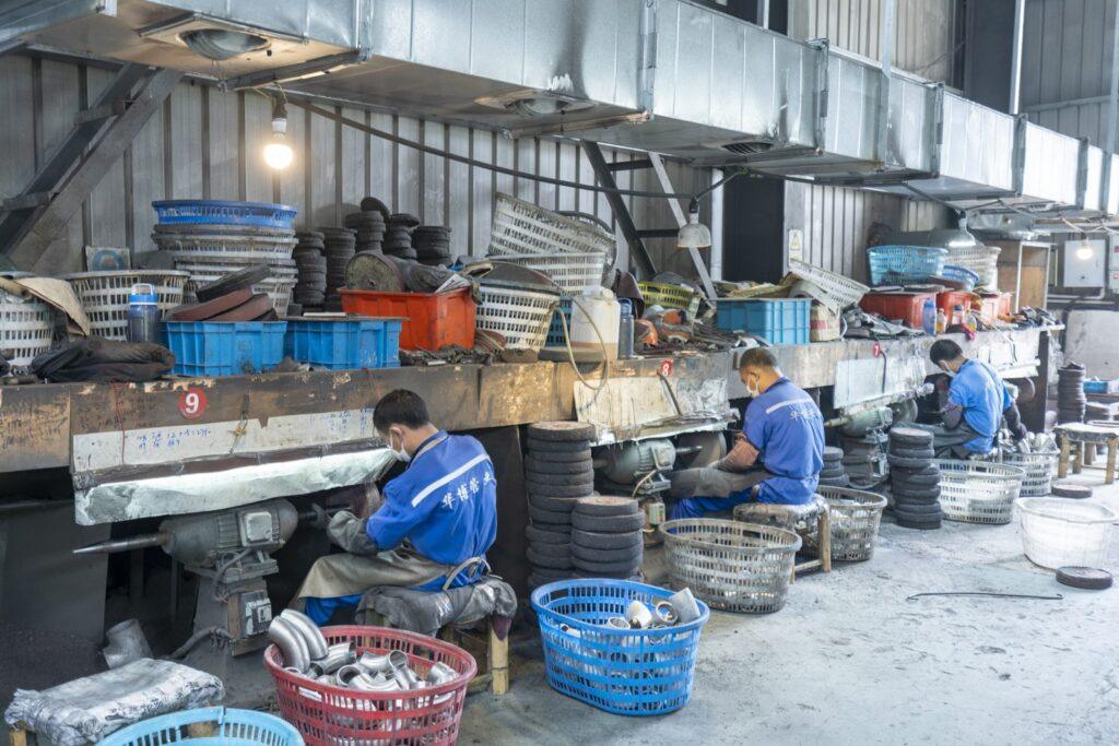 Workers grinding and finishing stainless steel fittings in the workshop