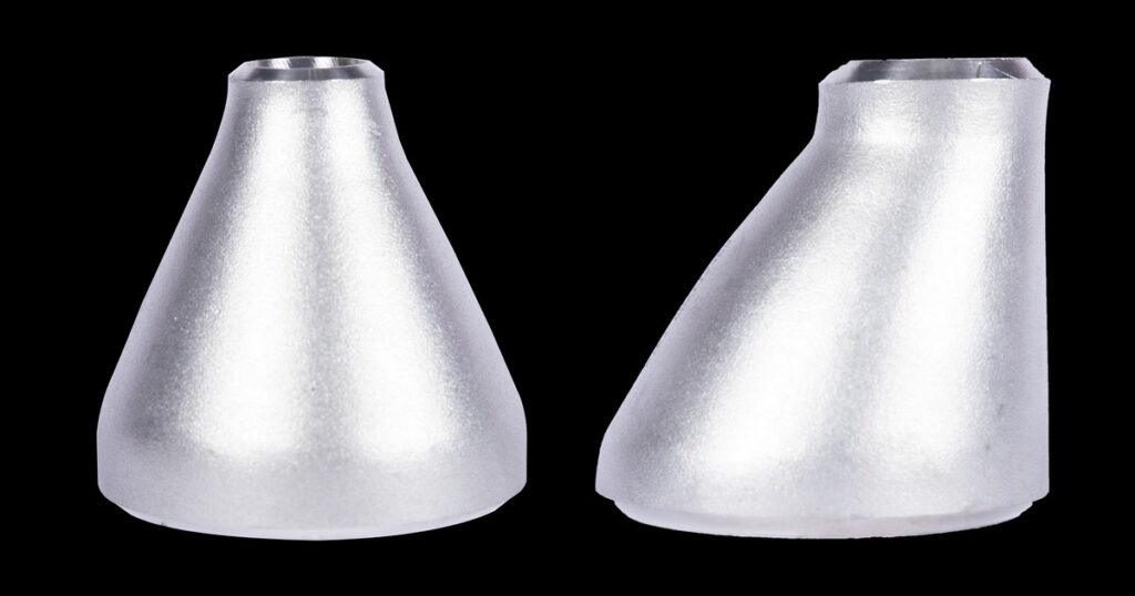 Stainless steel concentric reducer (left) and eccentric reducer (right) side by side, showing the symmetric cone versus the one flat side.