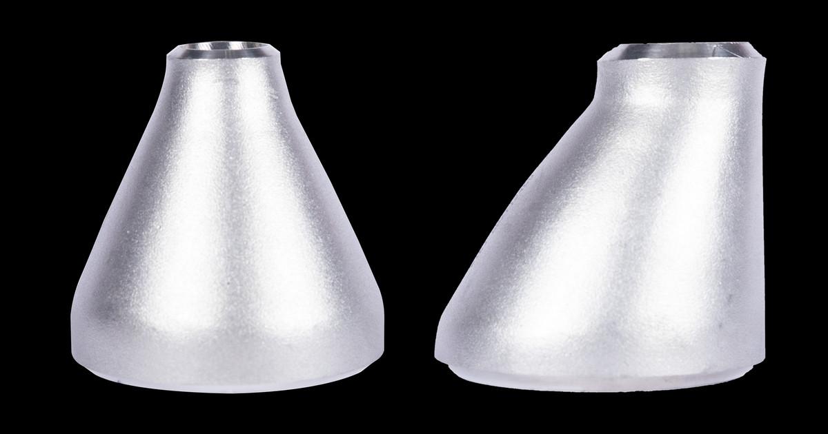 Stainless steel concentric reducer (left) and eccentric reducer (right) side by side, showing the symmetric cone versus the one flat side.