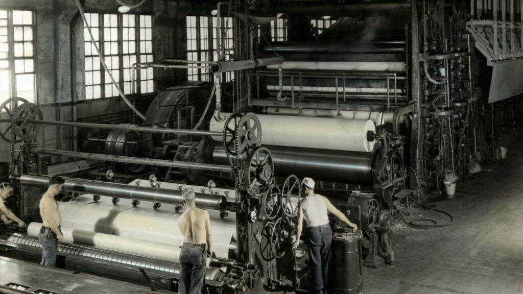 Paper machine with large paper rolls in a paper mill (historic photo)
