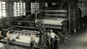 Paper machine with large paper rolls in a paper mill (historic photo)