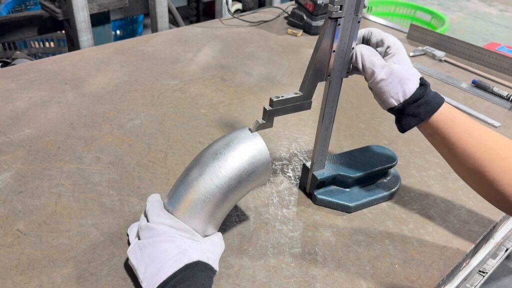 Height gauge checking the center-to-end dimension of a stainless steel elbow