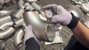 Dial thickness gauge measuring the wall thickness of a stainless steel elbow