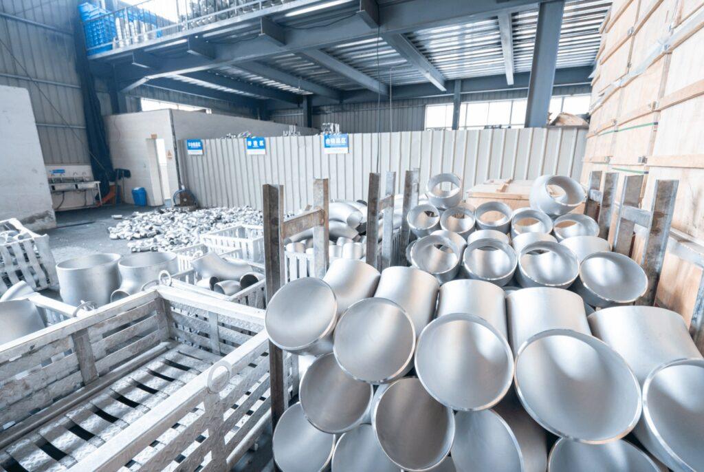 Large-diameter stainless steel butt-weld elbows stored in steel racks in the warehouse