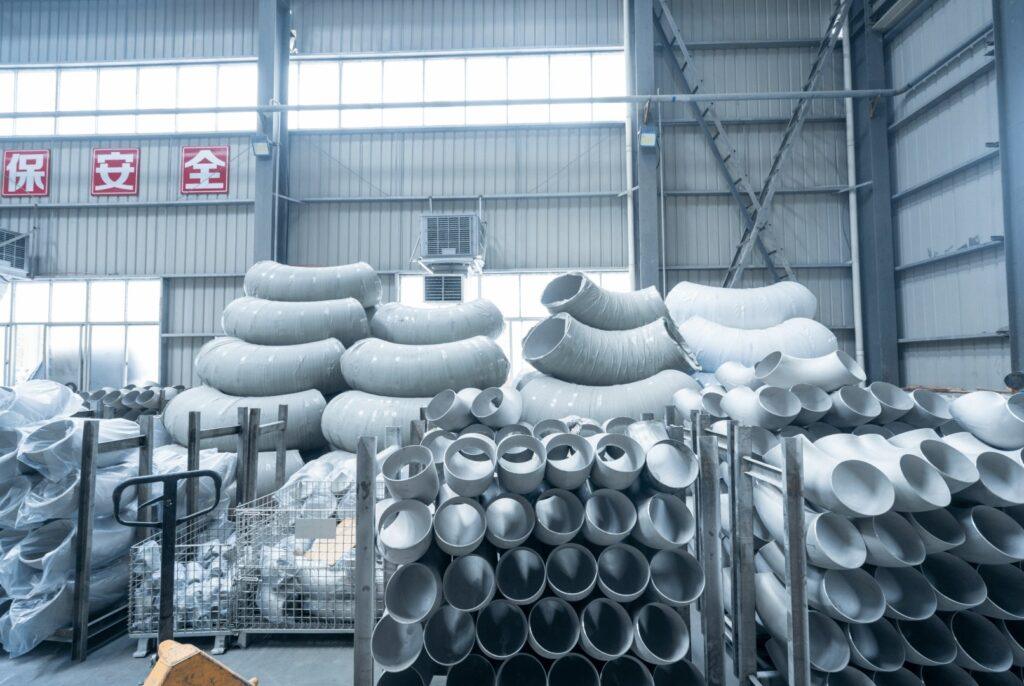 Stainless steel butt-weld elbows and large-radius bends stored on racks in the warehouse