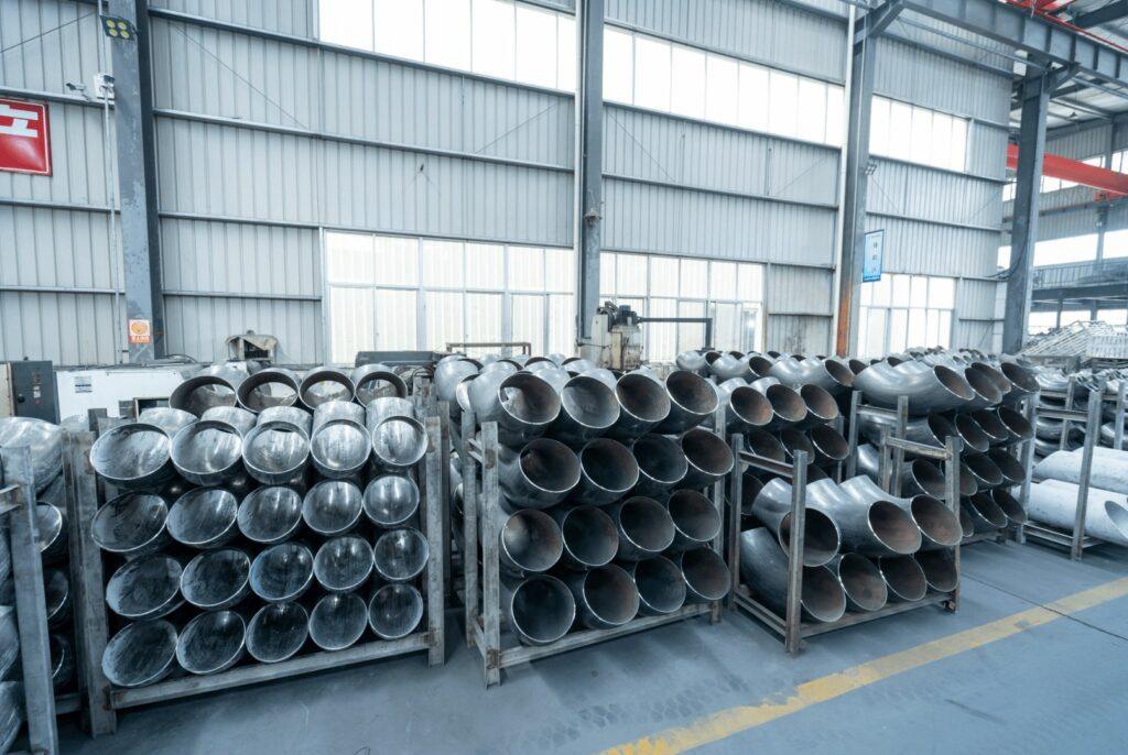Rows of stainless steel butt-weld elbows on racks in the fittings workshop
