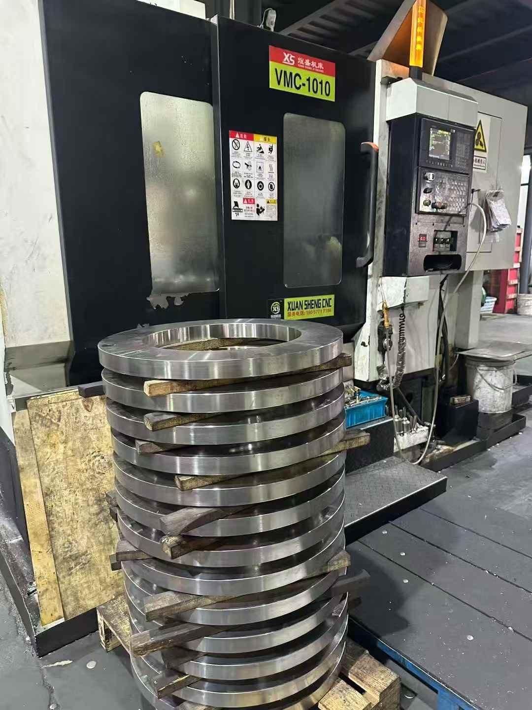 Stainless steel flange rings beside a CNC machining centre at the HuaboPipe factory in Lishui